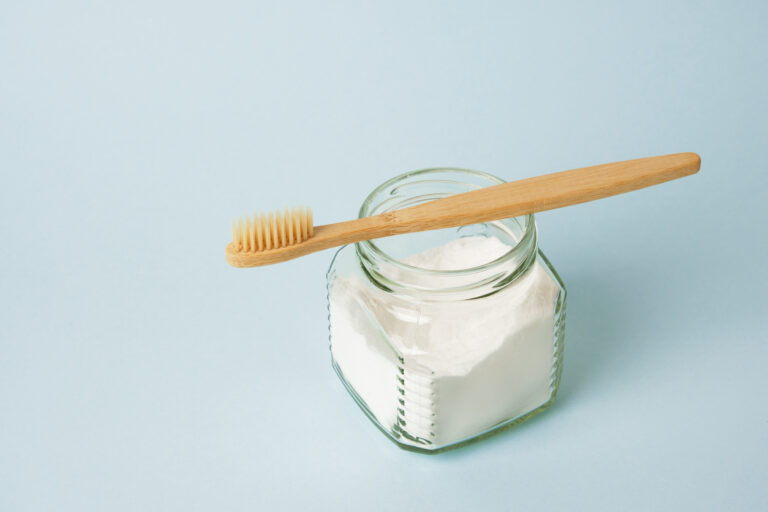 bamboo toothbrush and a can of soda on a light blue background
